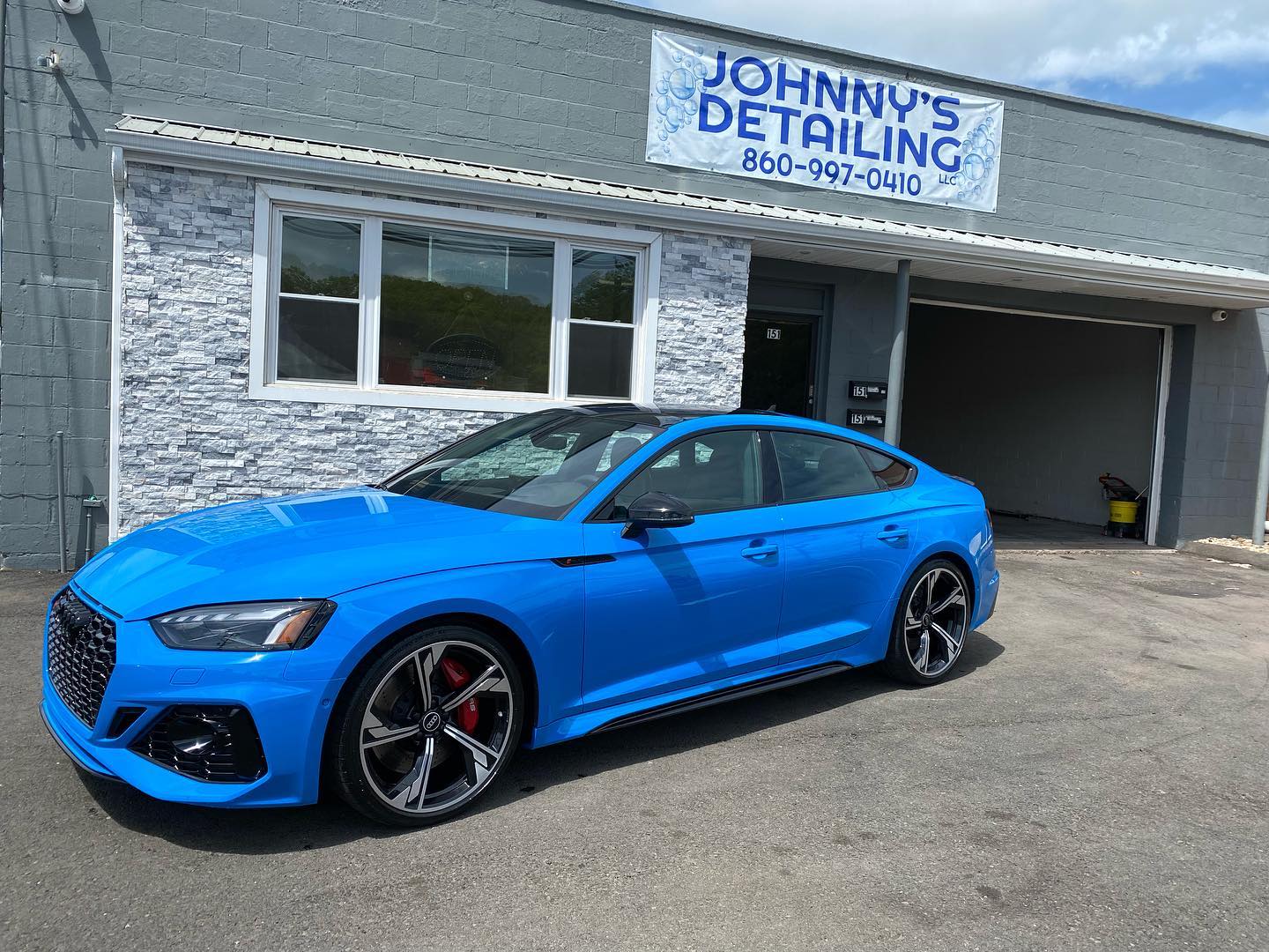 Bright blue Audi RS5 detailed in front of the shop