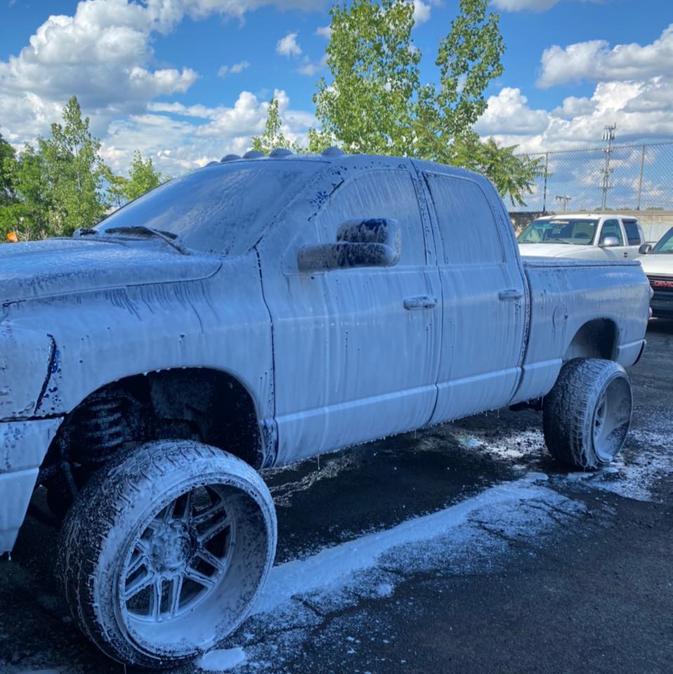 Lifted truck covered in white foam during the wash process